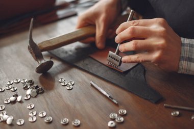 Stüdyodaki adam deri eşya üretiyor.