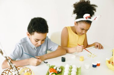 Sarı elbiseli çocuklar Paskalya yumurtalarını boyar