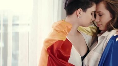 Evde bayraklı homoseksüel çift sarılıyor.