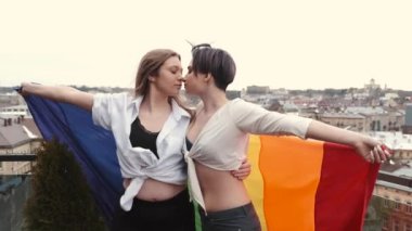 Evde bayraklı homoseksüel çift sarılıyor.