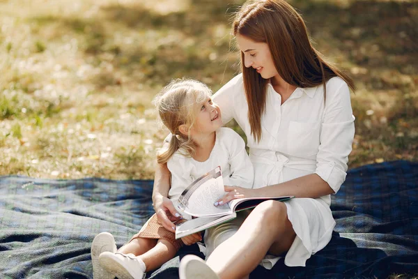 Madre con su hijita sentada en un cuadros y leyendo el libro — Foto de Stock