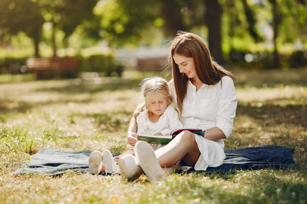 Madre con su hijita sentada en un cuadros y leyendo el libro — Foto de Stock