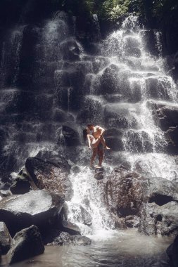 Çift büyük bir şelalenin altında duruyor.