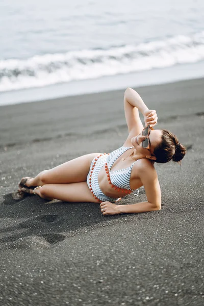 スタイリッシュな水着の女の子はビーチで休息を持っています — ストック写真