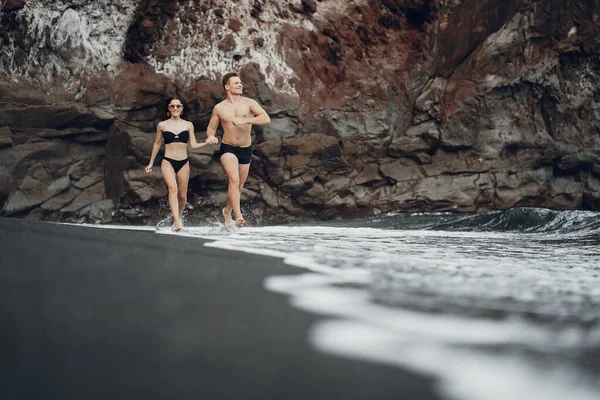 Elegante coppia su una spiaggia vicino a scogli — Foto Stock