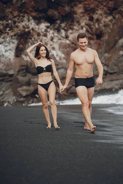 Elegante coppia su una spiaggia vicino a scogli — Foto Stock