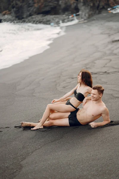 Элегантная пара на пляже возле скал — стоковое фото