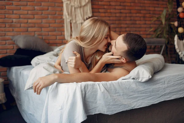 Casal sentado em uma cama em um quarto — Fotografia de Stock