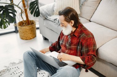 Üst düzey bir adam oturma odasında dizüstü bilgisayarla çalışıyor.