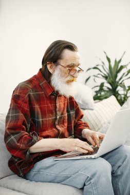 Üst düzey bir adam oturma odasında dizüstü bilgisayarla çalışıyor.