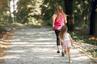 Anne ve kızı yaz parkında oynuyorlar.
