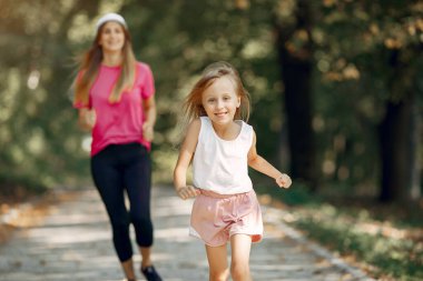 Anne ve kızı yaz parkında spor yapıyor.