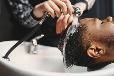 Genç Afro-Amerikalı adam berber dükkanını ziyaret ediyor.