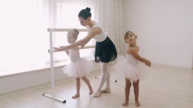 Dans okulundaki hocanın yardımıyla iki küçük kız bale barında koreografi çalışması yapıyor.