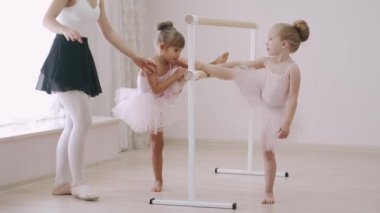 Dans okulundaki hocanın yardımıyla iki küçük kız bale barında koreografi çalışması yapıyor.