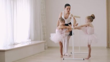 Dans okulundaki hocanın yardımıyla iki küçük kız bale barında koreografi çalışması yapıyor.
