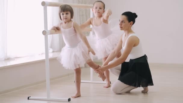 Duas meninas praticando elementos coreográficos no ballet barre com a ajuda do professor na escola de dança — Vídeo de Stock