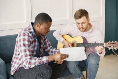Gitar çalan Afrikalı ve beyaz adam.