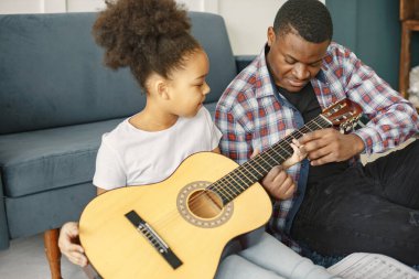Afrikalı baba kızına gitar çalmayı öğretiyor.