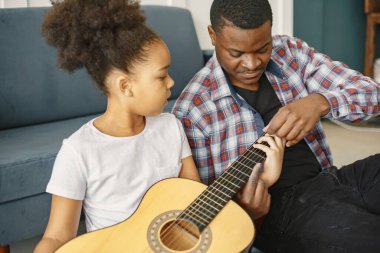 Afrikalı baba kızına gitar çalmayı öğretiyor.