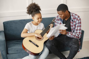 Afrikalı baba kızına gitar çalmayı öğretiyor.