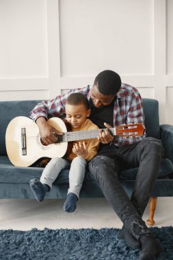 Baba oğluna gitar çalmayı öğretiyor.
