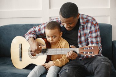 Baba oğluna gitar çalmayı öğretiyor.