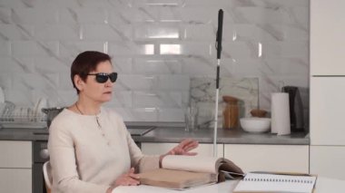 Kör, olgun bir kadın evde kör alfabesiyle kitap okuyor.