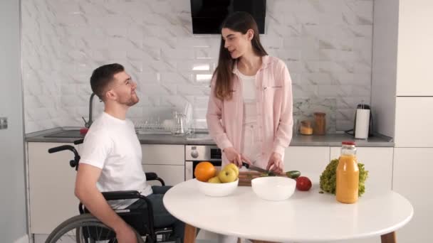 Femme encourager mari handicapé assis en fauteuil roulant à la table de cuisine — Video