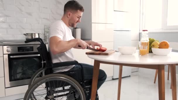 Jeune homme handicapé en fauteuil roulant préparant la nourriture dans la cuisine — Video