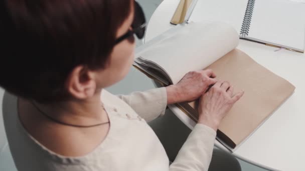 Ciego mujer madura leyendo braille libro en casa — Vídeo de stock