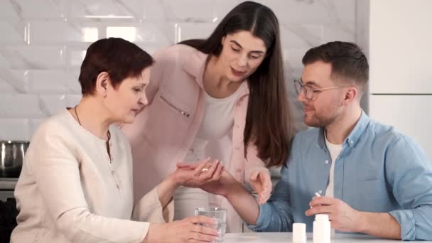 Couple helping disabled mother take in medicines — Stock Video