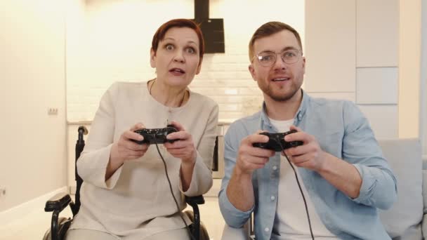 Behinderte Seniorin spielt Videospiele mit Sohn — Stockvideo