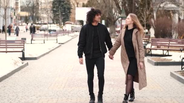 Young man and woman strolling on city square — Video
