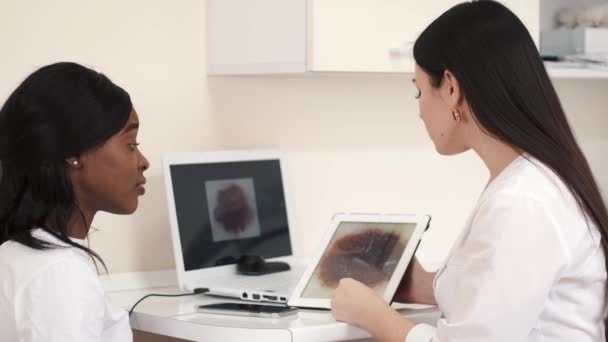 Woman with tablet computer explaining something to client — Stock video