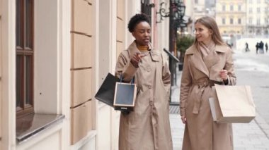 Alışveriş çantalı iki genç kadın ne aldıklarını kontrol ediyor.