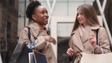 Alışveriş çantaları taşıyan güzel kızlar alışveriş merkezinden çıkıyorlar.