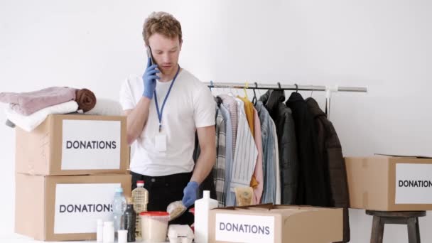 Молодой волонтер проверяет шкатулку для пожертвований и делает заметки, гуманитарную помощь — стоковое видео