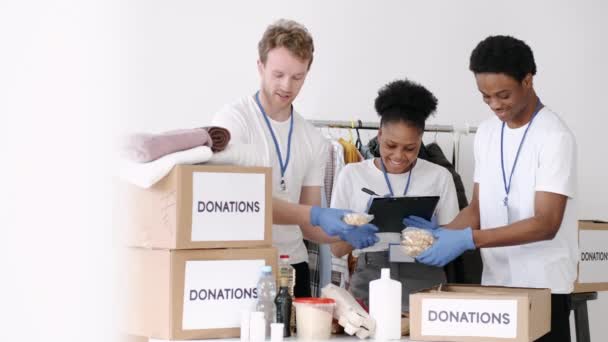 Diverse vrijwilligers voor het goede doel sorteren via gedoneerde goederen — Stockvideo