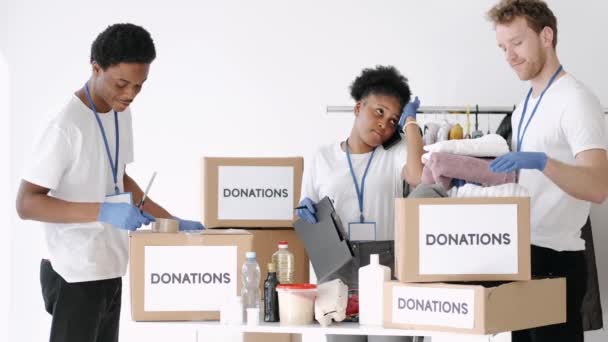 Diversos voluntarios de caridad clasificando a través de bienes donados — Vídeos de Stock