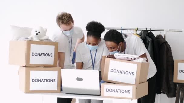 Bénévoles portant des masques triant les dons de vêtements pendant la pandémie — Video