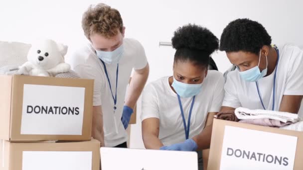 Добровольцы в масках сортируют пожертвования во время пандемии — стоковое видео