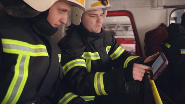 Dwóch strażaków analizujących dane na tablecie cyfrowym w kabinie ciężarówki — Wideo stockowe