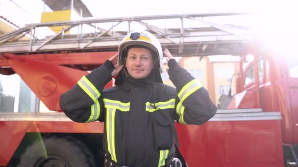 Пожежник відклав шолом після роботи, стоячи біля вантажівки — стокове відео