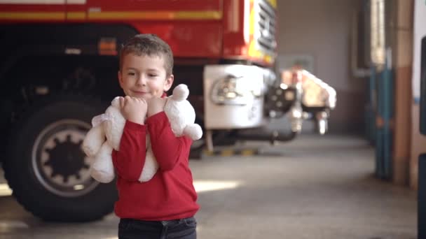 Маленька дівчинка тримає іграшку, що стоїть на пожежній охоронній станції — стокове відео