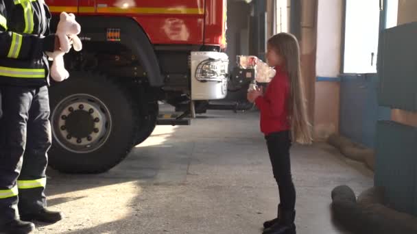 Pompier donnant un jouet à une petite fille à la station — Video