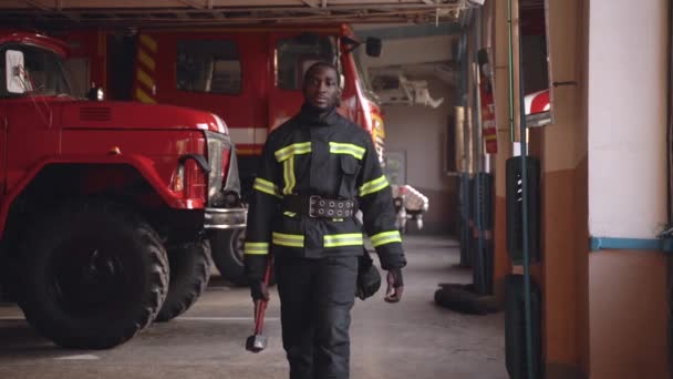 Чёрный пожарный готовится к экстренному вызову на станции — стоковое видео