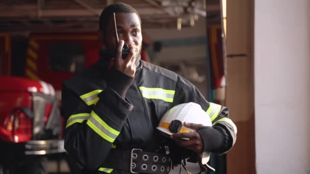 戴头盔的非裔美国消防员在消防局使用对讲机 — 图库视频影像