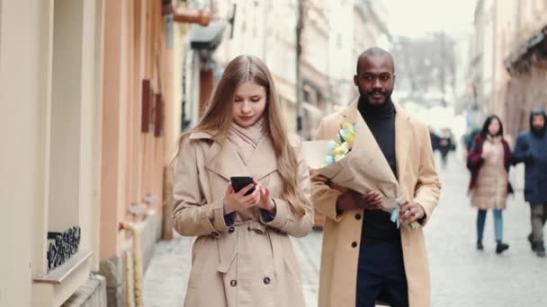 Hombre afroamericano sorprendiendo a su novia con flores en la calle — Vídeo de stock