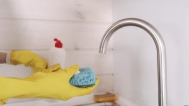 Eldivenli kadın mutfak odasında bulaşık yıkıyor.